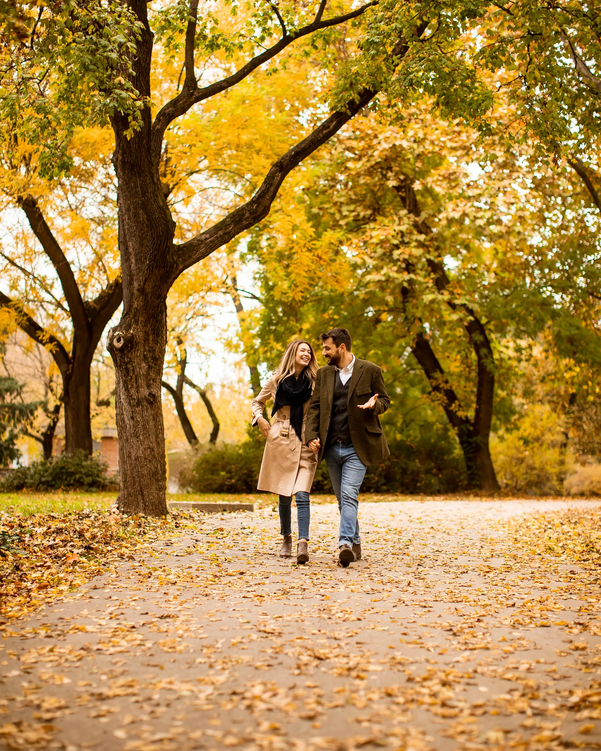 Paar spaziert Hand in Hand durch einen herbstlichen Park