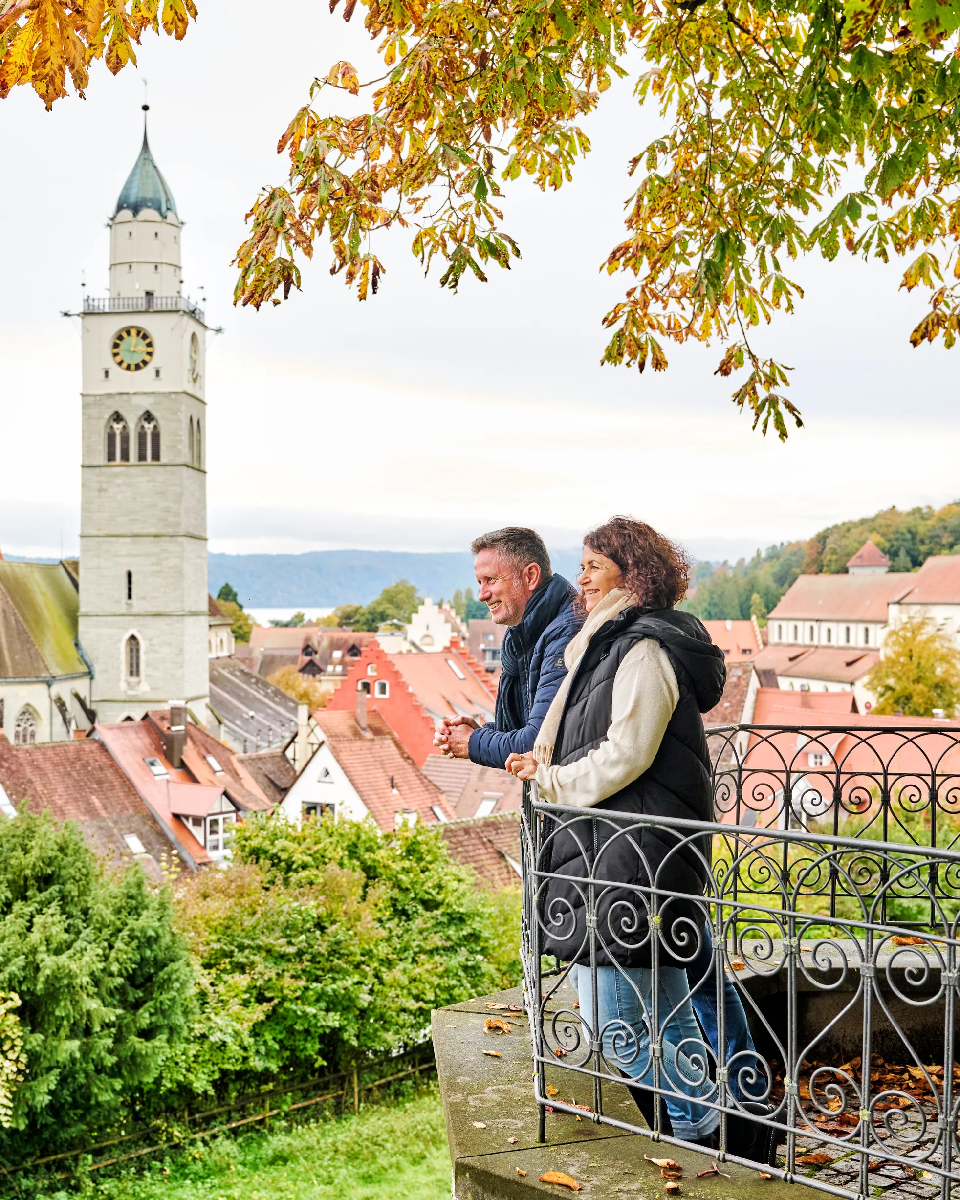 Paar an einem Aussichtspunkt über der Altstadt von Überlingen mit dem Münster, im Herbstlaub