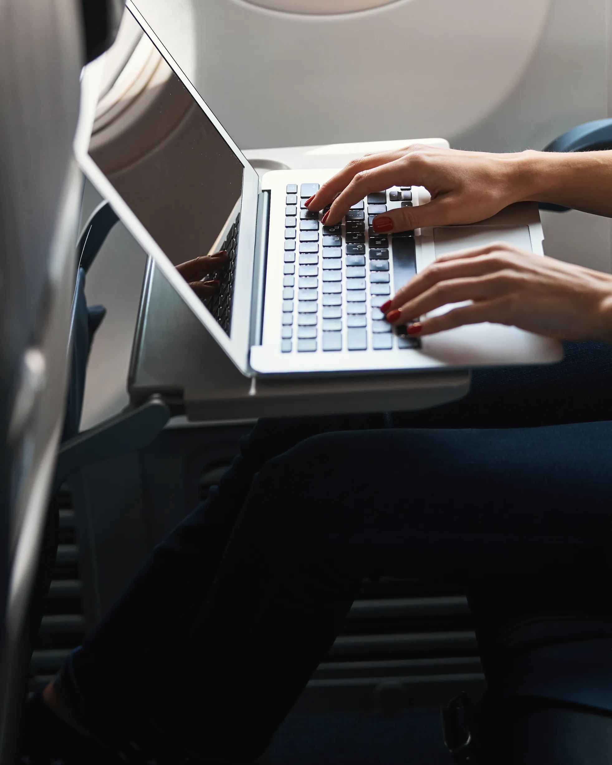 Reisende arbeitet am Laptop auf dem Tisch ihres Flugzeugsitzes